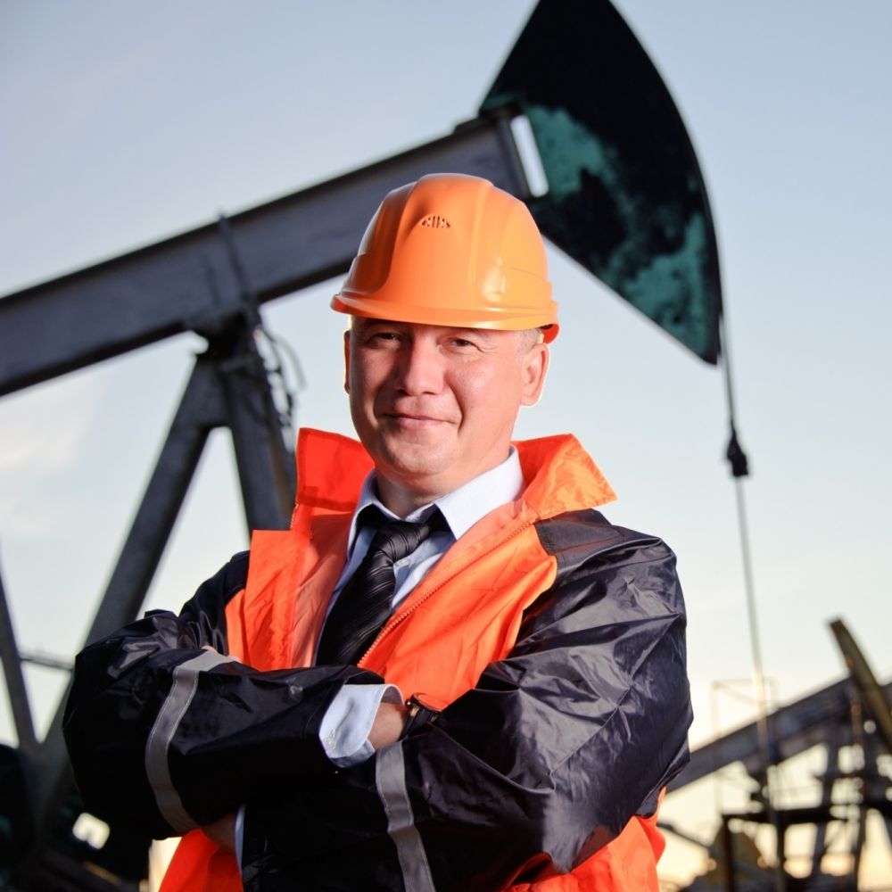 male business manager stands in front of row of pumpjacks