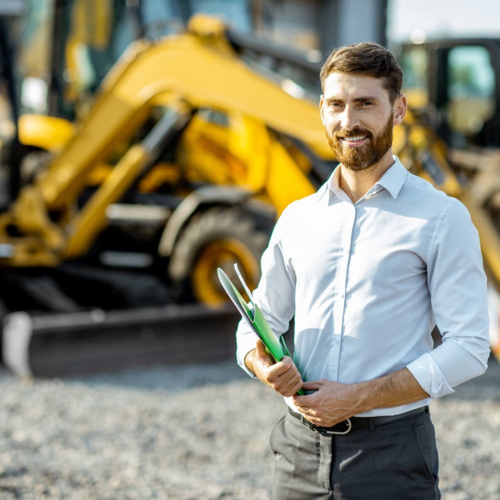 male worker standing in front of heavy equipment