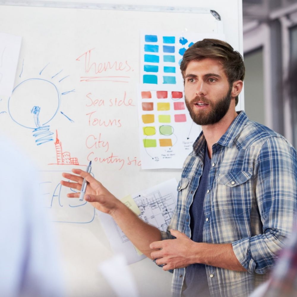 casual young man leads marketing strategy session using whiteboard and sticky notes